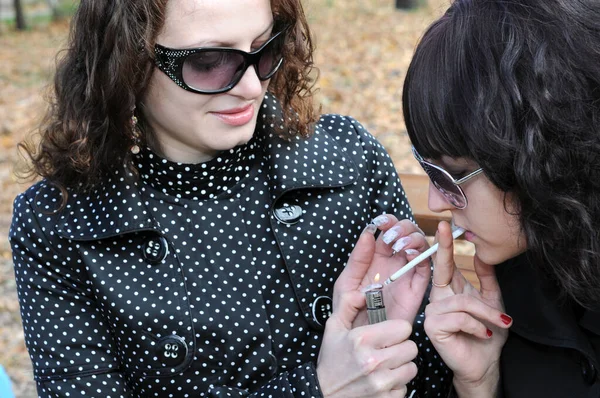 Δύο Νεαρές Γυναίκες Χαλαρώνουν Στο Πάρκο Φθινόπωρο Και Καπνίζουν Τσιγάρα — Φωτογραφία Αρχείου