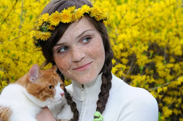 close-up portrait of happy freckled girl and red cat in the spring park