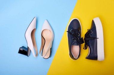 İki çift modern kadın ayakkabısına yakın çekim: siyah topuklu açık beyaz topuklular ve mavi-sarı arka planda sıradan lacivert spor ayakkabılar. Moda blogu veya dergi konsepti.