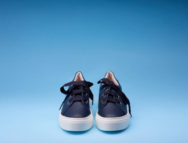 Rahat kadın lacivert spor ayakkabıları mavi eğimli arka plana odaklı. Uzayı kopyala Ayakkabı ile yaratıcı minimalist yerleşim.