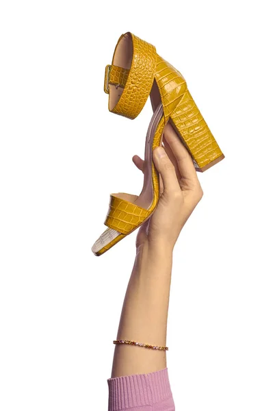 白い背景に隔離された高いブロックヒールを持つ黄色い爬虫類の革の夏のサンダルを保持する女性の手 スタイリッシュな靴のプレゼンテーション — ストック写真