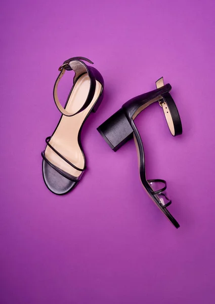 Glamorous open-toe women\'s shoes with block heels, clear vamps, ankle straps and beige insoles, isolated on a purple background. Fashion photography