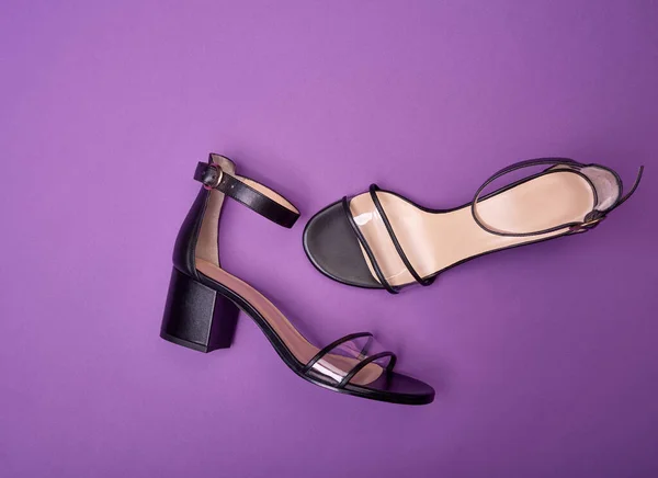 Stylish open-toe women\'s shoes with block heels, clear vamps, ankle straps and beige insoles, isolated on a purple background. Fashion photography