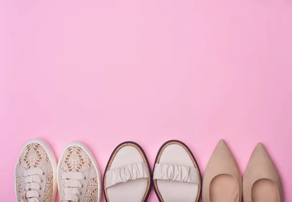 上部と中央にコピースペースを備えたパステルピンクの背景にベージュ女性の夏の靴のバリエーション スタイリッシュなスニーカー サンダル ポンプ フラットレイ トップビュー ファッションブログや雑誌のコンセプト — ストック写真