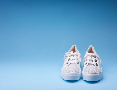 Renkli mavi arka planda kalın kauçuk tabanlı modaya uygun beyaz deri ayakkabılar. Uzayı kopyala Ayakkabı ile yaratıcı minimalist yerleşim.