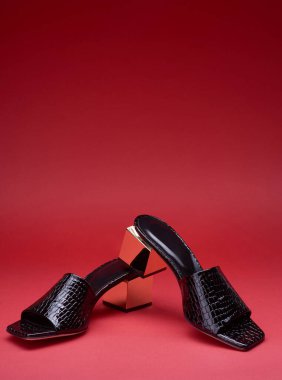 Süslü kadınların açık parmaklı siyah terlikleri. Timsah derisi dokular ve altın metalik topuklar. Gradyan pembe arka planda izole edilmiş ve fotokopi alanı var. Modern ve moda bir ayakkabı mağazası..