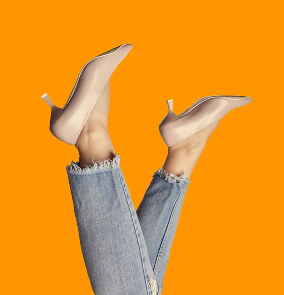 トレンディなパステルポンプとジーンズを着た女性の足のファンキーな写真は 明るいオレンジ色の背景に隔離された逆さまに 夏の靴や服を販売するためのマーケティングキャンペーン ファッションブログ — ストック写真