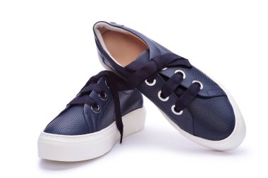 Kalın beyaz bir platform ve geniş ayakkabı bağcıkları ile donanımlı lacivert spor ayakkabılar. Parlak pembe bir arka planda izole edilmiş ve metin için fotokopi alanı var. Reklam afişi, ayakkabı satışı, moda fotoğrafçılığı.