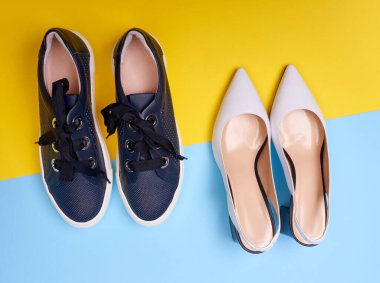 İki çift modern kadın ayakkabısı: açık-sırt beyaz topuklu siyah işaret fişeği topuklu ve mavi-sarı arka planda lacivert spor ayakkabılı. Üst manzara, yakın plan. Yaz sezonu ayakkabı konsepti