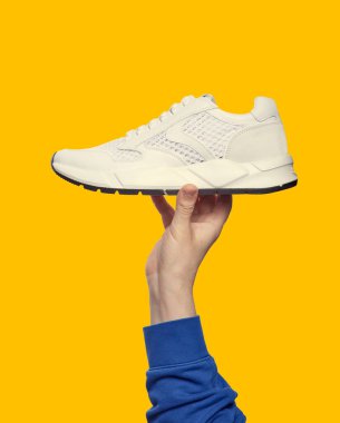 Parlak sarı arka planda çalışan beyaz spor ayakkabıları ve fotokopi alanı var. Kapatın. Outlet pazarlama posteri