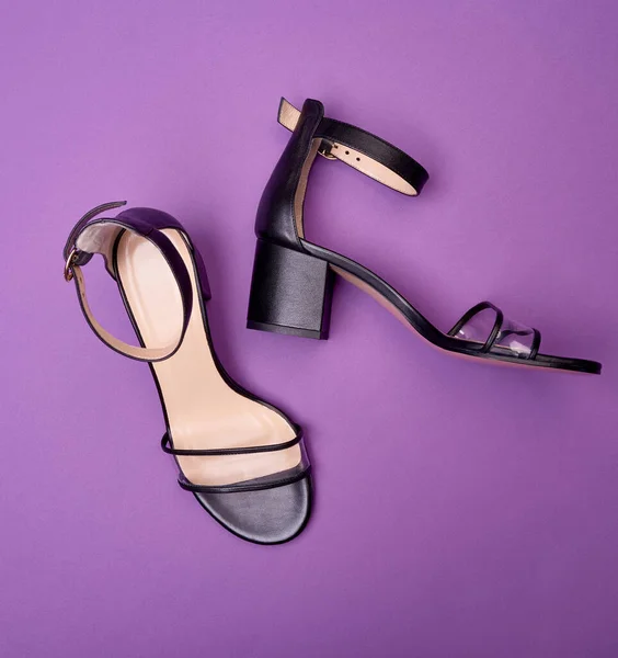 Close up view of cool open-toe women\'s shoes with block heels, clear vamps, ankle straps and beige insoles, isolated on a purple background. Fashion photography