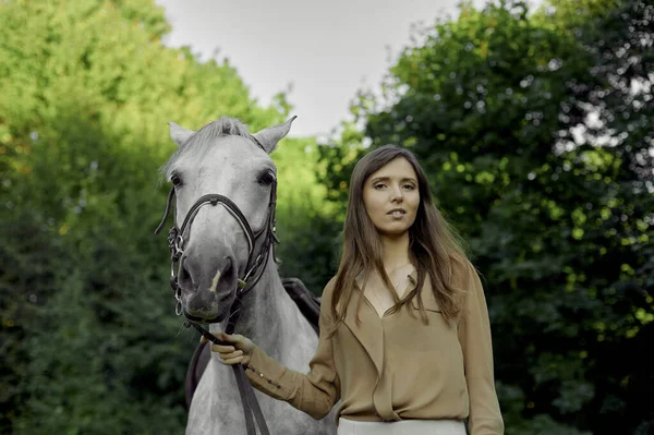 骑着马上学 希波疗法 马疗法 一个年轻的漂亮女人的画像 她在森林里骑着一匹结了花边的青苹果灰色的马 与动物的沟通和联系 海马疗法 — 图库照片