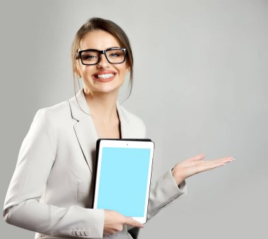 Gülümseyen genç bir kadın yeni ürün ya da tanıtım metni için fotokopi alanını gösterirken dijital tabletin ekranını gösteriyor. Özel tasarım için boş mavi ekran. Reklam anlaşması..