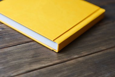 Sarı kapaklı fotobook, ahşap arka planda fotokopi alanı ile izole edilmiş. Bakış açısı. Özel metin ya da resim yerleştirmek için boş kapalı kitap modeli. Fotoshoot 'tan baskı fotoğrafları tanıtılıyor.