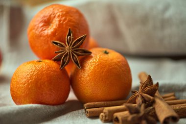 Keten bir masa örtüsü üzerinde olgun bir mandalina kümesine tarçın çubukları ve yıldız anason eşlik eder. Yakın çekim görüntüsü. Baharatlı İçecek Hazırlama.