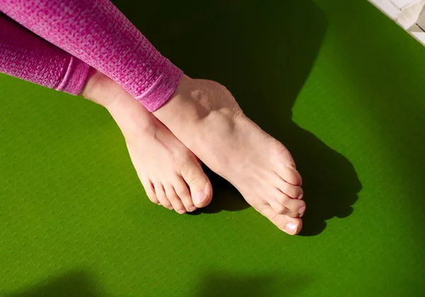 筋肉のストレスを和らげるためにマッサージを受けた後 女性の足は緑のヨガマットでリラックスしています 筋肉の痛みを軽減し 血流を増加させる 生理療法 リフレクソロジー 柔軟性プロモーション — ストック写真