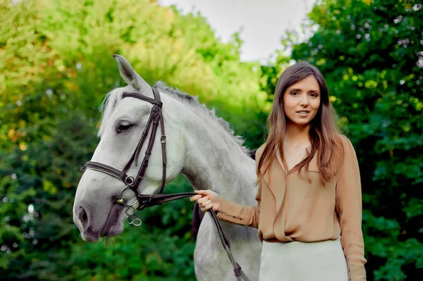 年轻的骑师女孩领着一匹骑着的棕色马骑在马背上 学校提供骑马课和治疗经验 如海马疗法 动物交流 关心马的情感健康 — 图库照片