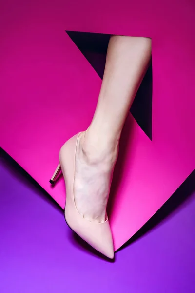 Graceful female leg displaying high-heel pastel patent leather pump via vivid magenta paper triangle cutout. Design for a fashion blog or magazine. Discount promotion poster for e-commerce store.