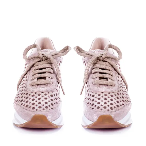 A pair of female sneakers from dusty pink leather with perforation and shiny effect and white-pink-brown sole isolated on a white background. Footwear sales advertising campaign.