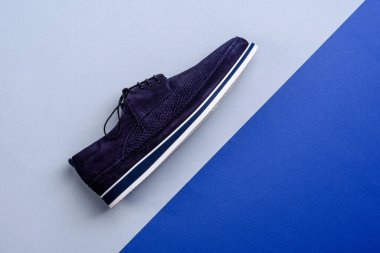 Modern koyu mavi renkli süet erkek ayakkabısının yan görünüşü beyaz ve mavi tabanlı ve yaratıcı geometrik arka planda kopya alanı ile izole edilmiş. Reklam afişi için bir model. Moda eğilimi.