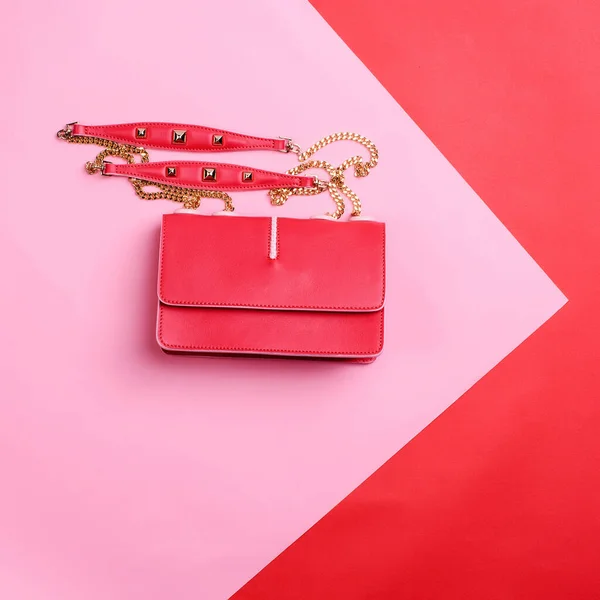 Modern red leather female bag with a gold shoulder chain isolated on a pink-red graphic background with copy space. Discount promotion poster for an e-commerce store. Fashion blogger content.