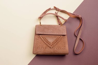 Kadınların şık, omuz bantlı kahverengi süet çantası. Orijinal delinme dekorasyonu, fotokopi alanı olan iki tonluk ilginç bir arka planda sergileniyor. Çantalı yaratıcı minimalist düzen.