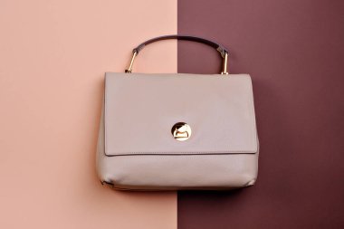 Üst kulplu zarif bir bayan deri çanta ve iki tonluk mavi arka planda altın bir donanım. İndirim, sezon satışları. Perakende, mağaza, butik. Moda blogu veya dergi konsepti.