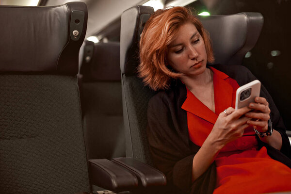 Молодая красивая женщина путешествует на поезде, сидя у окна, используя мобильный смартфон. Устал от долгой поездки. Чтение в социальных сетях мобильных телефонов, уведомлений, сообщений или видео.