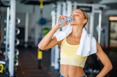 Spor salonunda çalıştıktan sonra su içen bir kadının portresi.