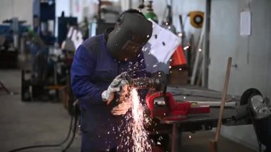 Açı öğütücü kullanan ve kıvılcım saçan bir işçi. 