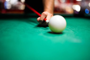 Bilardo oynayan genç adam, iyi bir atış yapmayı hedefliyor. 