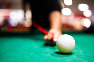 Bilardo oynayan genç adam, iyi bir atış yapmayı hedefliyor. 