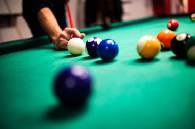 Bilardo oynayan genç adam, iyi bir atış yapmayı hedefliyor. 