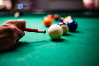 Bilardo oynayan genç adam, iyi bir atış yapmayı hedefliyor. 