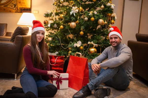Noel Baba Şapkalı Bir Çift Evde Noel Ağacının Yanında Oturuyor — Stok fotoğraf