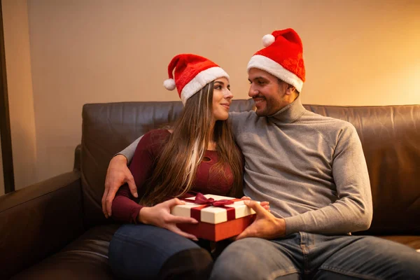 Junges Paar Nikolausmützen Öffnet Ein Weihnachtsgeschenk — Stockfoto