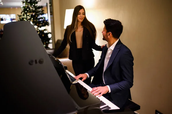Snygg Man Som Spelar Piano För Sin Flickvän Julafton — Stockfoto