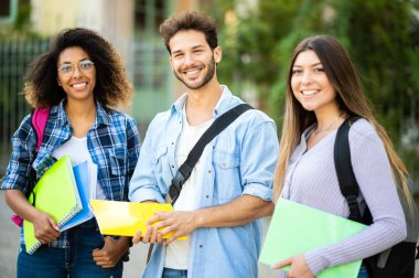 Dışarıda gülümseyen çok ırklı bir grup öğrenci.