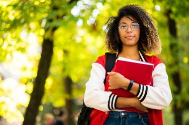 Üniversite parkında kitap tutan Afrikalı bir kız öğrenci.