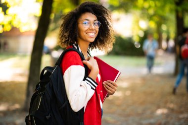 Üniversite parkında kitap tutan Afrikalı bir kız öğrenci.