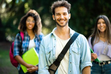 Dışarıda gülümseyen çok ırklı bir grup öğrenci.