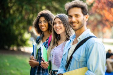 Dışarıda gülümseyen çok ırklı bir grup öğrenci.