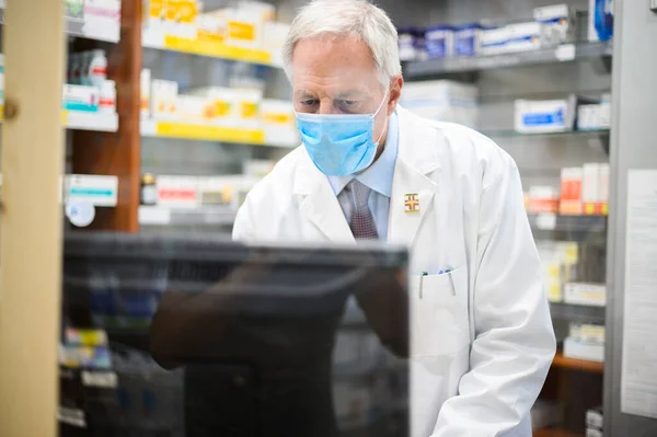 Pharmacist at work with a computer in his store