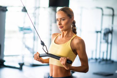 Spor salonunda çalışmak için makine kullanan bir kadın.