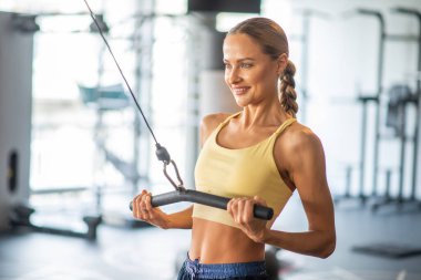 Spor salonunda çalışmak için makine kullanan bir kadın.