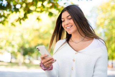 Akıllı telefonunu kullanırken parkta yürüyen kadın