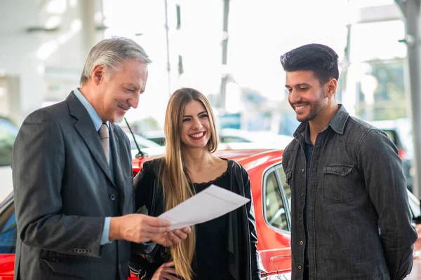 Szczęśliwa Młoda Rodzina Rozmawia Sprzedawcą Wybiera Nowy Samochód Salonie — Zdjęcie stockowe