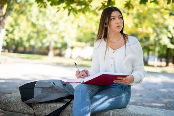公園で本を勉強して書く若い女性 — ストック写真