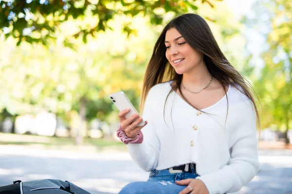 スマートフォンを使いながら公園を歩く女性 — ストック写真