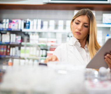 Genç bir kadın eczacı eczanenin envanterini kontrol ediyor.